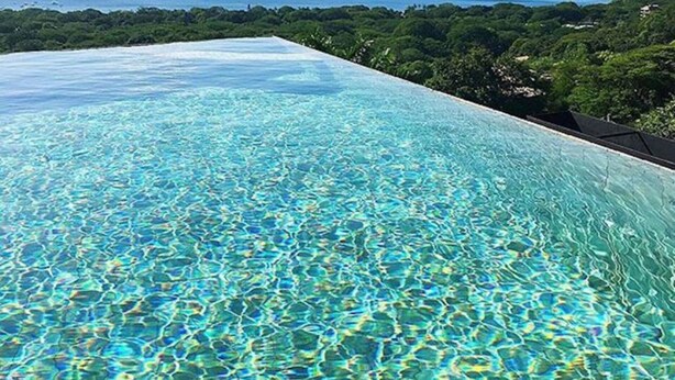 An infinity pool with clear blue water and a view of the ocean and greenery. - Casa de los Suenos (Sardinal)