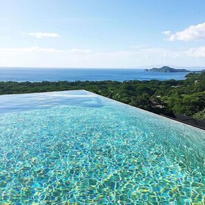 An infinity pool with clear blue water and a view of the ocean and greenery. - Casa de los Suenos (Sardinal)