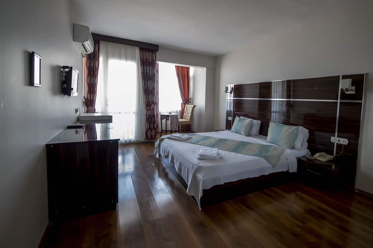 Una habitación de hotel moderna con una cama grande, una mesita de noche y un escritorio con una silla.