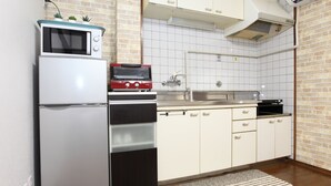 A compact kitchen with a refrigerator, microwave, oven, and sink. - Kujo no Yado Great House Osaka (Osaka)
