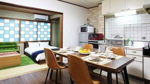 A compact hotel room with a bed, a dining table set for two, a kitchenette, and a sliding door leading to a balcony. - Kujo no Yado Great House Osaka (Osaka)