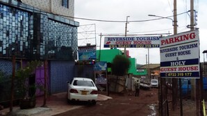 A guest house with a signboard advertising Riverside Tourism and a contact number. - Riverside Tourism Guest House (Embu)