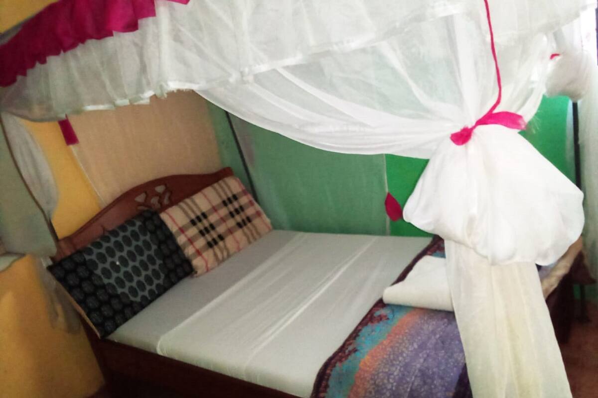 Una cama con un colchón blanco, una manta colorida y un mosquitero.