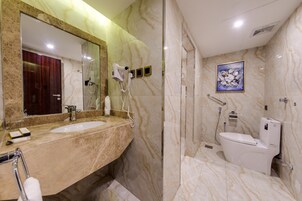A modern bathroom with a marble vanity, a large mirror, a hairdryer, and a toilet.