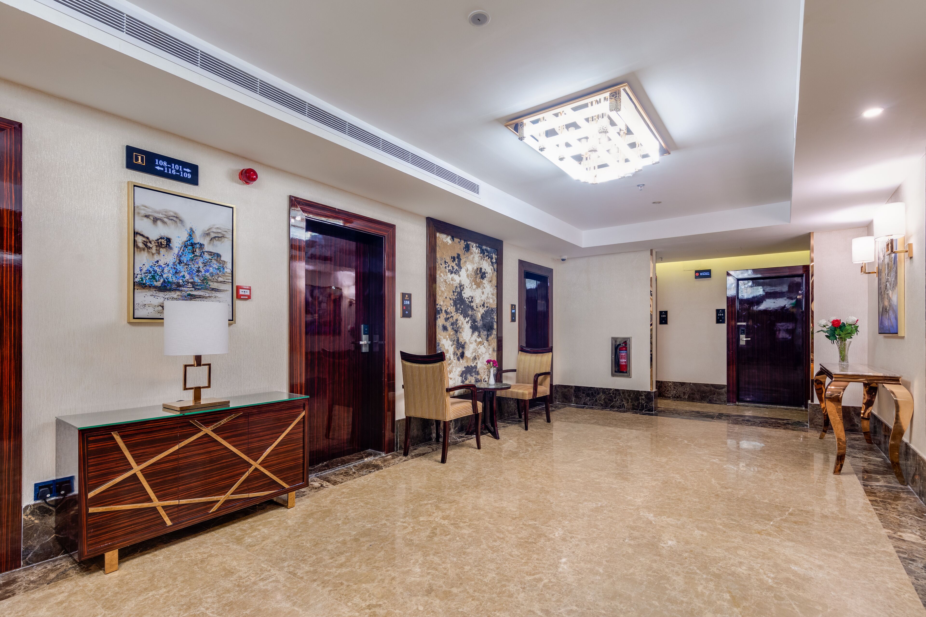 Un vestíbulo con piso de mármol, muebles de madera y obras de arte en las paredes.