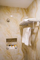 Ein Badezimmer mit Marmorwänden, einem Handtuchhalter und einer Ablage für Toilettenartikel.