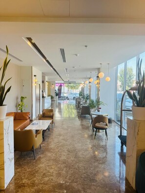 A modern interior with a long corridor, seating areas, and large windows. - Al Ertiqaa Hotel (Jeddah)