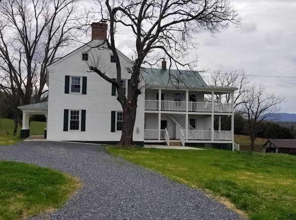 A two-story white house with a covered porch and a staircase leading to the upper level.
