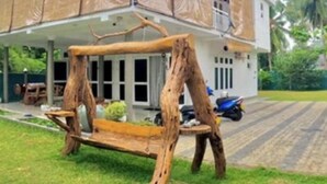 A house with a covered porch and a wooden swing set in the foreground. - Villacork (Galle)
