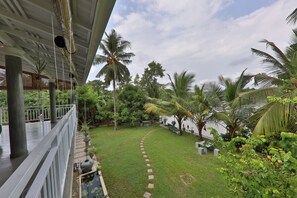 A covered outdoor area with a pathway, palm trees, and various plants. - Villacork (Galle)