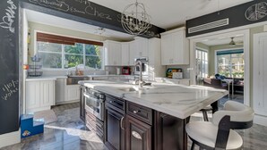 A modern kitchen with white cabinets, a large island with a sink, stainless steel appliances, and a chandelier. - 4/6bd SPACIOUS, Heart of Miami Beach! Mediterranean Villa w/Jacuzzi, HUGE YARD! (Miami Beach)