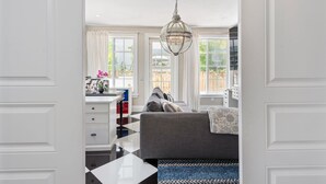 A well-lit room with a large window, a sofa, a desk with a chair, and a hanging light fixture. - 4/6bd SPACIOUS, Heart of Miami Beach! Mediterranean Villa w/Jacuzzi, HUGE YARD! (Miami Beach)