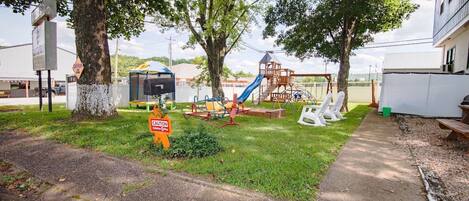 A playground with slides and swings, a mailbox, and a caution sign.