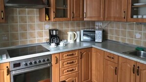 A kitchen with wooden cabinets, a gas stove, a microwave, and a coffee maker. - Diamonds Apartments (Budapest)