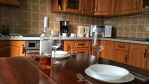 A kitchen with wooden cabinets, a granite countertop, a coffee maker, a kettle, a microwave, and a wine glass set. - Diamonds Apartments (Budapest)