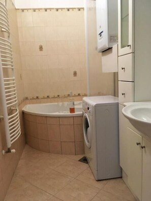Un baño pequeño con bañera, lavadora y lavamanos.