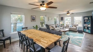 A spacious living room with a wooden dining table, two sofas, a coffee table, and a ceiling fan.