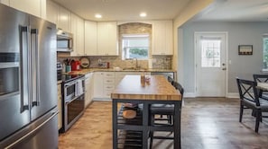 A modern kitchen with stainless steel appliances, a wooden island, and a view of the outdoors.