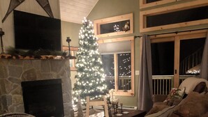 Ein gemütliches Wohnzimmer mit Kamin, Weihnachtsbaum und einer bequemen Couch.
