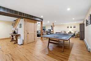 Une pièce spacieuse équipée d’une table de ping-pong, d’un parquet, d’un canapé et d’un bureau avec un ordinateur.