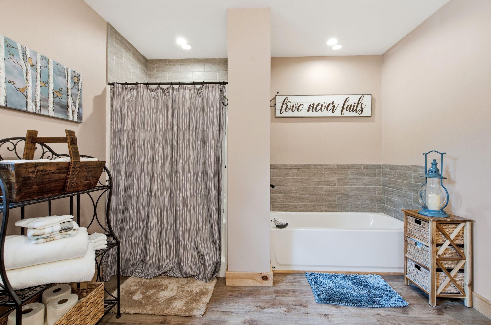 A bathroom with a bathtub, a shower curtain, a towel rack, and a sign that says 'love never fails'.