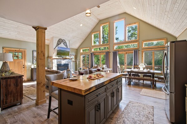 A spacious kitchen with a large island, wooden cabinetry, and a stone fireplace.
