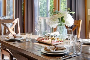 A wooden dining table set with plates, cutlery, glasses, and a floral centerpiece. - MLK weekend open! Guest favorite near Sunday River! (Bethel)