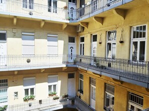 A multi-story building with balconies, windows with shutters, and potted plants. - Folk Art Apartment (Budapest)