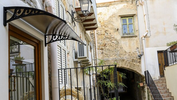 Une ruelle étroite avec une porte en bois, un portail en métal et un escalier menant à un étage supérieur.