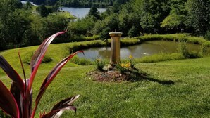 Un jardín con un estanque, un bebedero para pájaros y vistas a montañas.