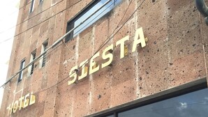 A hotel named "Siesta" with a large glass entrance, visible signage, and a reflection of palm trees and vehicles in the glass. - Hotel Siesta (Ixtaczoquitlán)