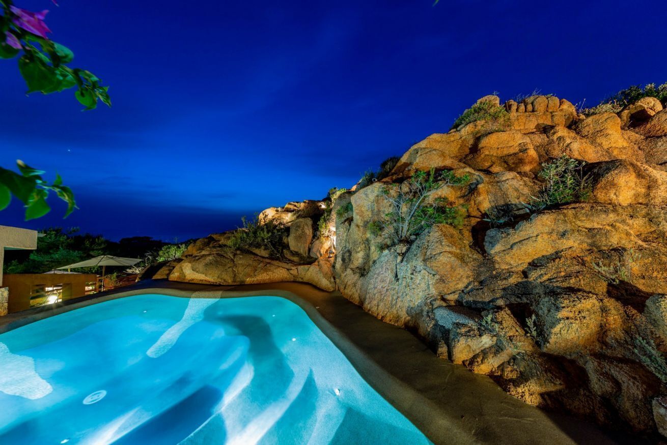 A swimming pool with a rocky landscape and a night sky.
