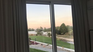A view through a sliding glass door to a well-maintained outdoor area with a lawn, garden beds, and a paved walkway. - Monte do Mosteiro CountryHouse (Batalha)
