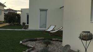 A modern house with a well-maintained lawn, a patio area with two lounge chairs, and a decorative stone feature. - Monte do Mosteiro CountryHouse (Batalha)
