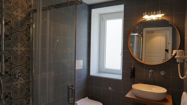 A modern bathroom with a shower, a sink, and a mirror.