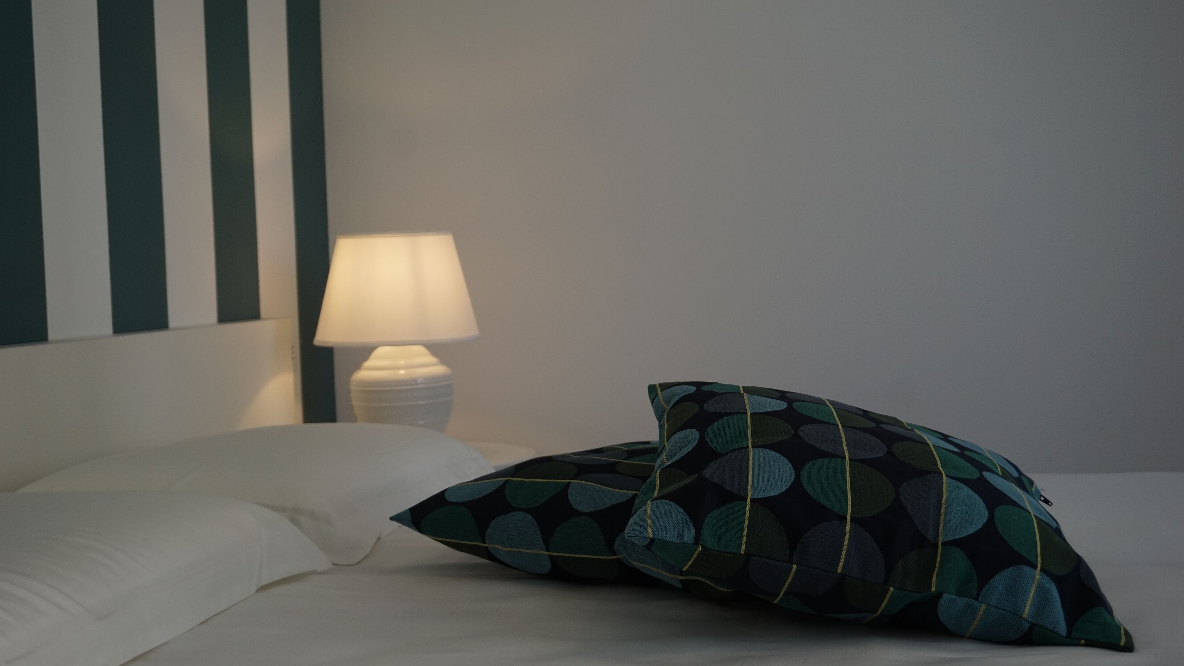 Ein Bett mit weißen Laken und einem Kissen mit einem Rundmuster.