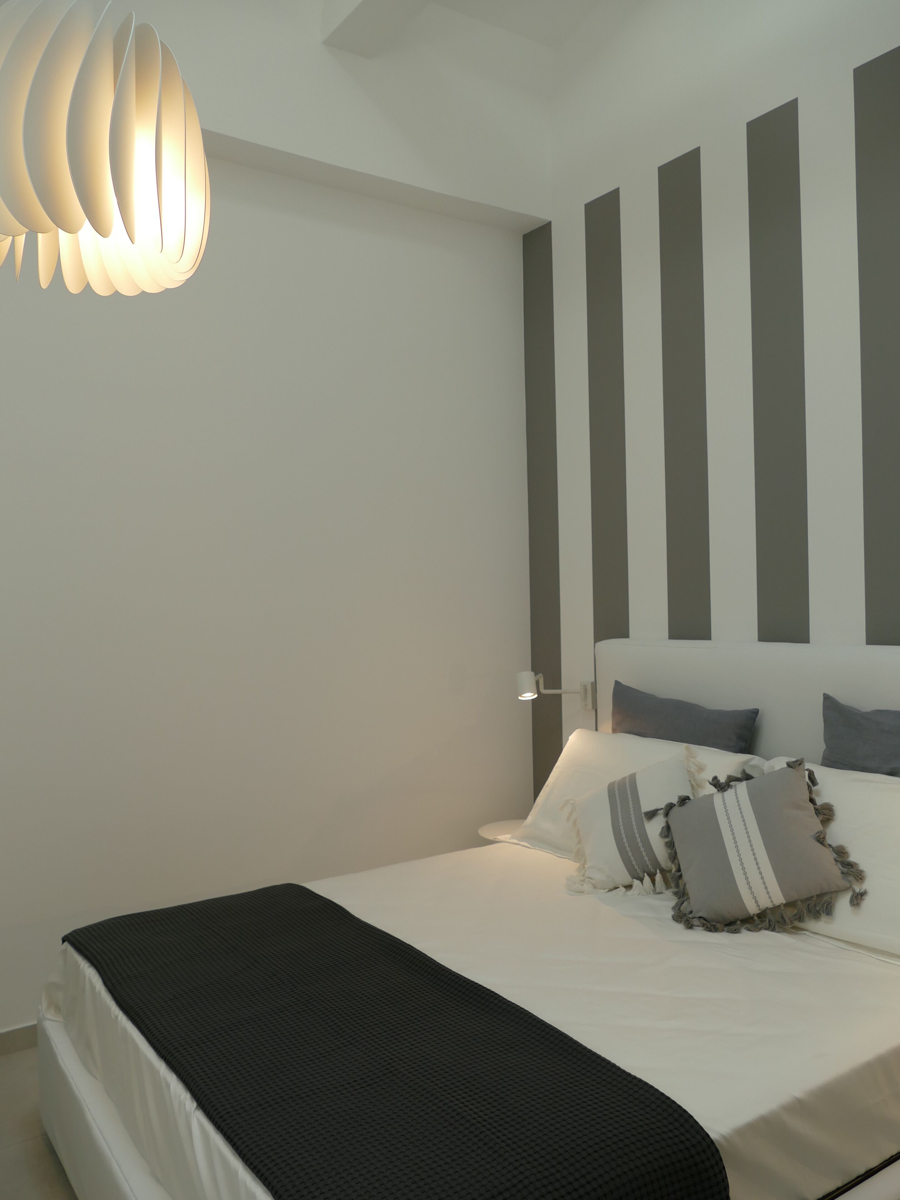 Un dormitorio moderno con una cama, una lámpara de noche y una lámpara de techo original.