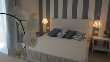 Una camera da letto con un letto, due lampade da comodino, un comodino con un vaso di fiori e una finestra con tende.