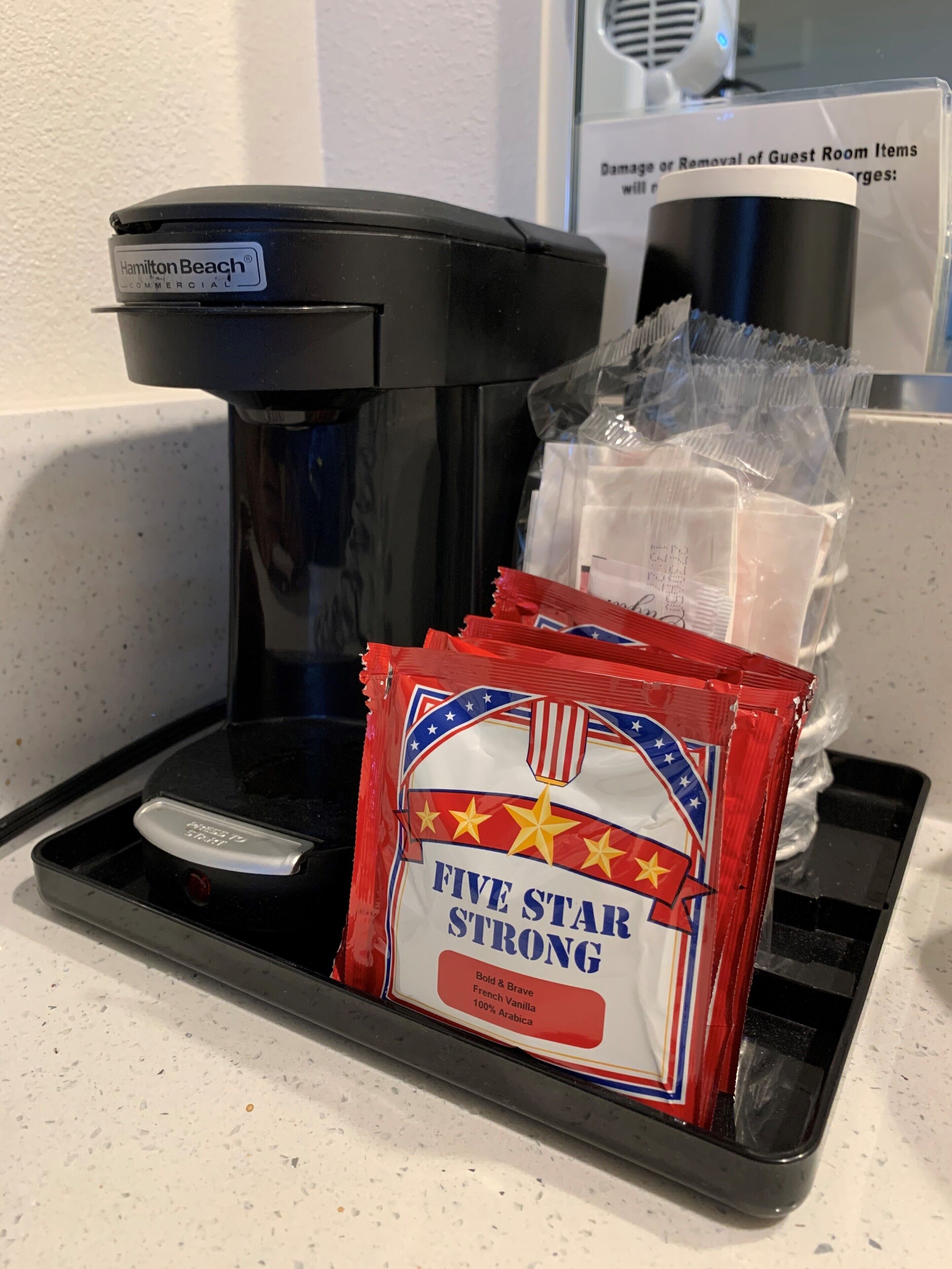 Una macchina da caffè, un sacchetto di caffè e un cartello che riguarda la rimozione degli oggetti dalle camere degli ospiti.