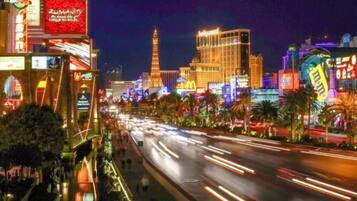 A nighttime view of a brightly lit street with neon signs and a prominent hotel building.