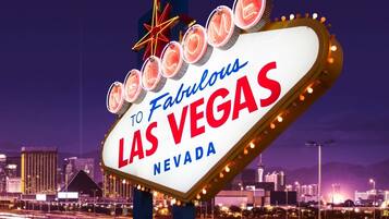 Un letrero de neón con el texto "Welcome to Fabulous Las Vegas Nevada" frente a un paisaje urbano nocturno.