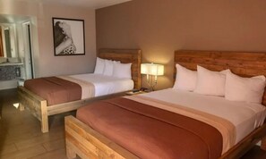 Two wooden beds with white linens, a wooden headboard, a bedside lamp, and a framed picture on the wall. - Bposhtels Las Vegas (Las Vegas)