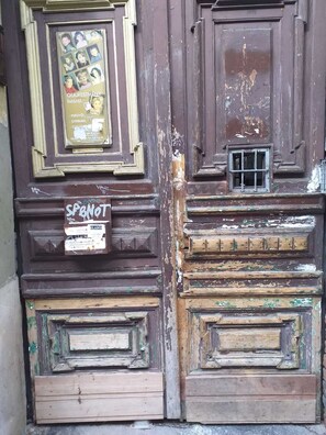 A weathered wooden door with peeling paint and a small window.