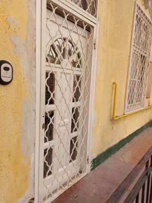 A yellow building with a white door featuring a decorative metal grille.