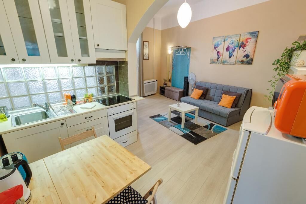 A compact living space with a kitchenette, a dining area, and a seating area with a sofa and a coffee table.