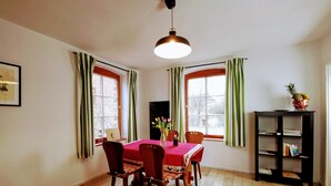 Een eethoek met een tafel, stoelen, een laptop en een boekenkast.