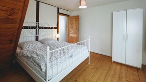 Een slaapkamer met een bed met wit metalen frame, een houten deur en een witte kledingkast.