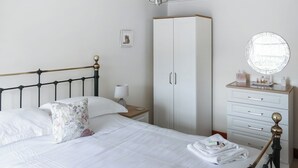 A neatly made bed with white linens, a bedside lamp, a wardrobe with a mirror, and a small bedside table with toiletries. - 2 bedroom accommodation in Redmire, near Leyburn (Redmire, near Leyburn)