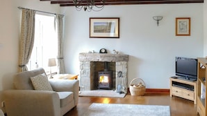 A living room with a stone fireplace, a sofa, a television, and a rug. - 2 bedroom accommodation in Redmire, near Leyburn (Redmire, near Leyburn)