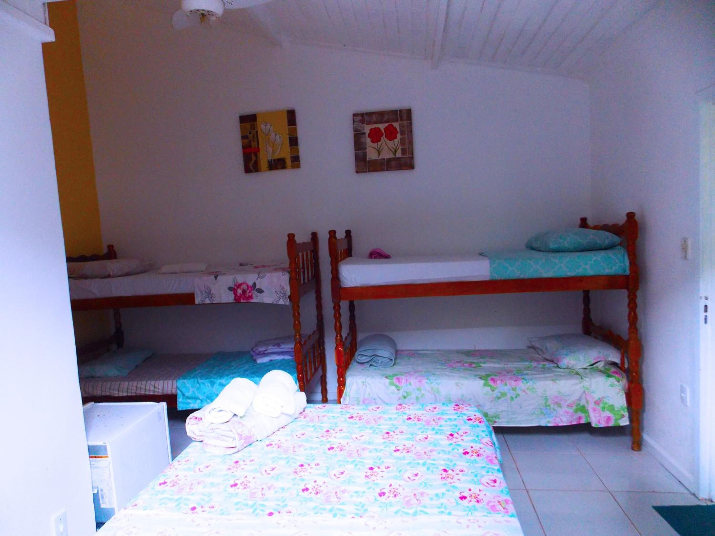 A dormitory room with bunk beds, a refrigerator, and two wall art pieces.